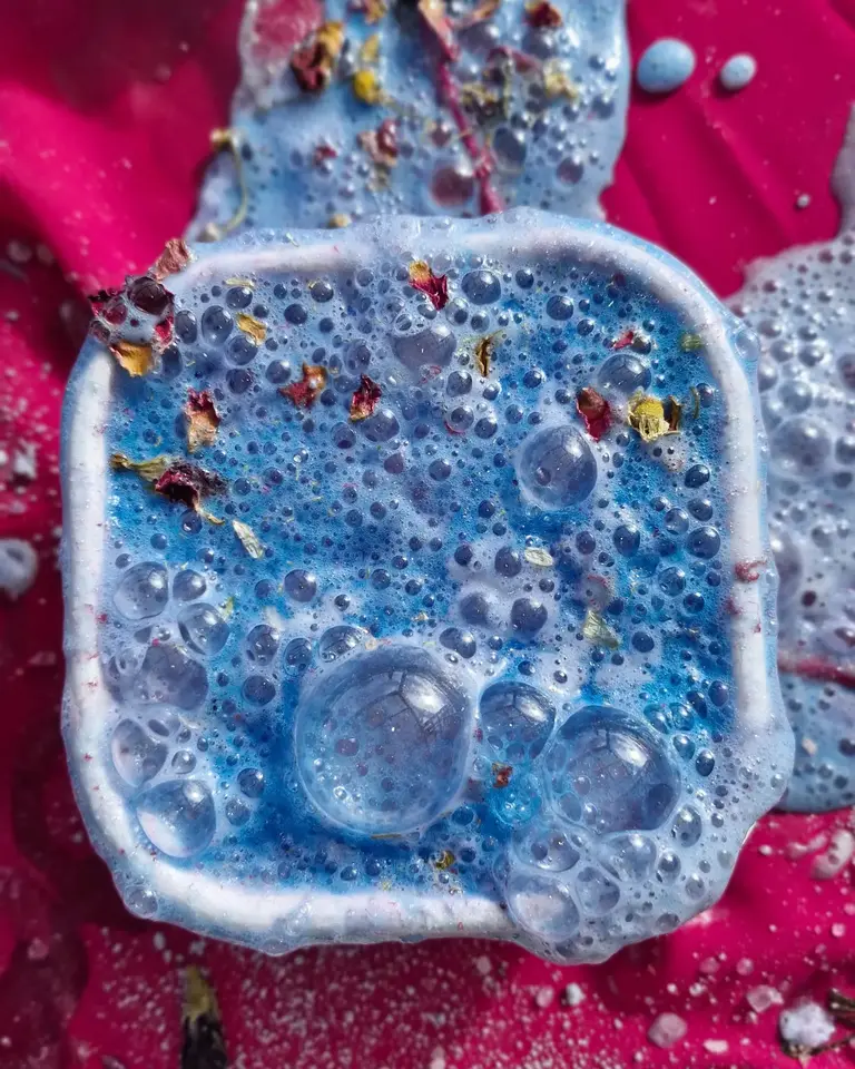 Foaming blue and purple Faerie Secrets potion with petals and glitter — handmade magical sensory potion play for kids and the young at heart.